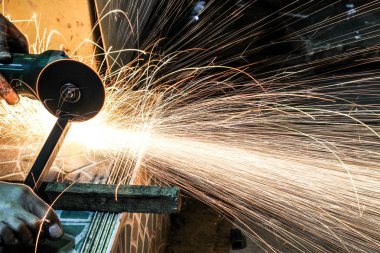  Öğütücüyle metal kesen bir işçi. Demir öğütürken kıvılcımlar