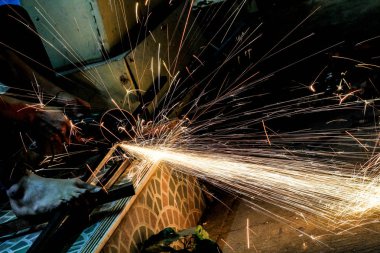  Öğütücüyle metal kesen bir işçi. Demir öğütürken kıvılcımlar