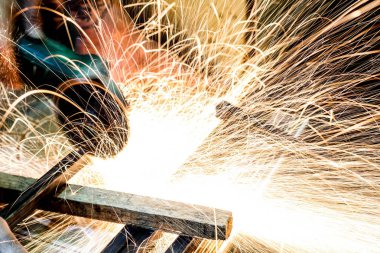  Öğütücüyle metal kesen bir işçi. Demir öğütürken kıvılcımlar