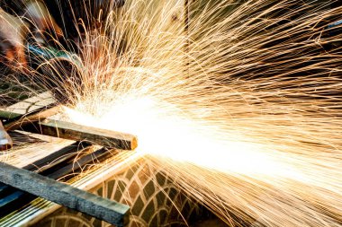  Öğütücüyle metal kesen bir işçi. Demir öğütürken kıvılcımlar