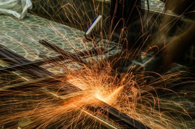  Öğütücüyle metal kesen bir işçi. Demir öğütürken kıvılcımlar