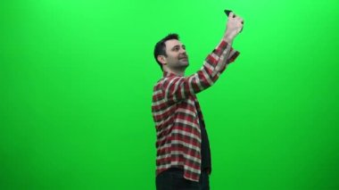 Adam yeşil bir ekran üzerinde onun Smartphone ile Selfie fotoğraf çekme