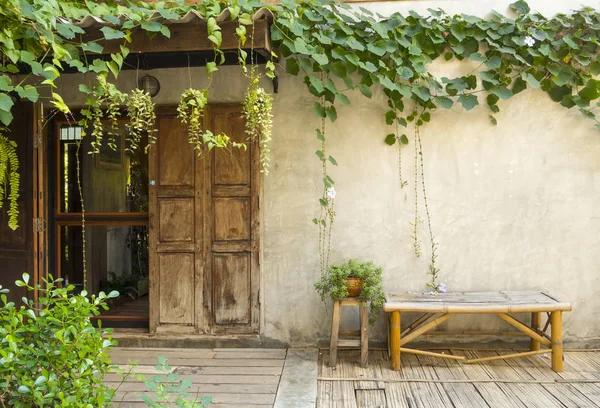 Puerta de madera y banco de bambú con planta verde — Foto de Stock