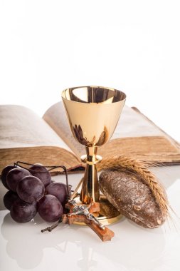 Açılan Holy Bible, altın chalice, üzüm, ekmek ve tahta haç ile Hıristiyan kompozisyon