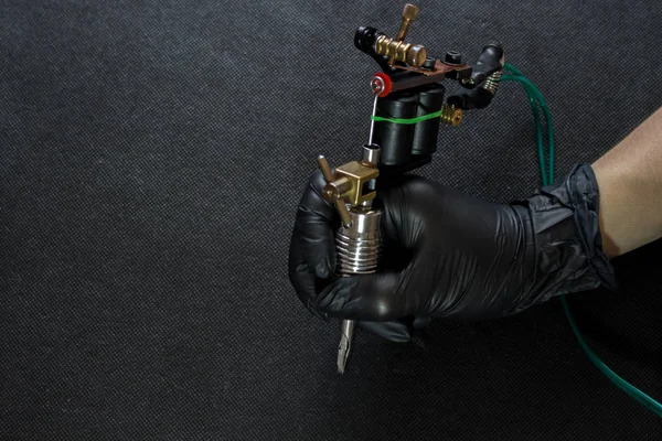 Koyu arka plan, bir dövme kavram için makine üzerinde dövme makinesi tutan dövme sanatçısı