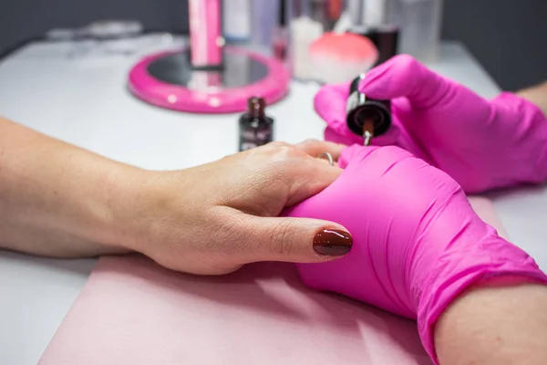 Closeup shot of a woman in a nail salon receiving a manicure by a beautician, Woman getting nail manicure, Manicure nail paint pink color