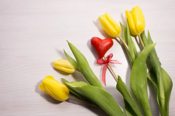Beyaz ahşap arka planda çiçek lalesi. Sarı lale çiçeklerinden bir buket. Sevgililer Günü konsepti, kadınlar günü. Kırmızı hediye kutusu.