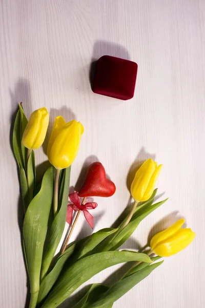 Flower tulip on white wooden background. Bouquet of the yellow tulip flowers. Valentines day concept, woman\'s day. Red gift box.