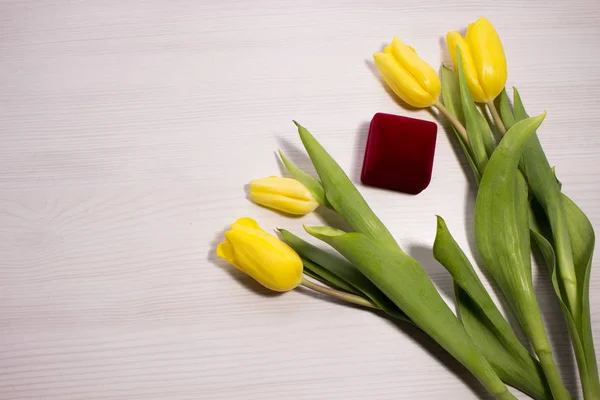 Flower tulip on white wooden background. Bouquet of the yellow tulip flowers. Valentines day concept, woman\'s day. Red gift box.