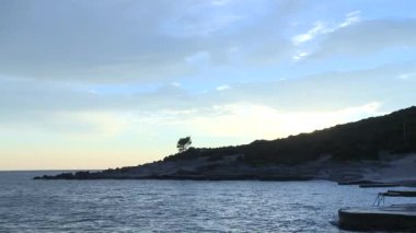 ağacın yanında deniz bulutlu gün batımı