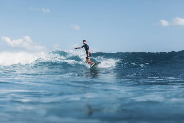 sportsman surfing wave on board in ocean 