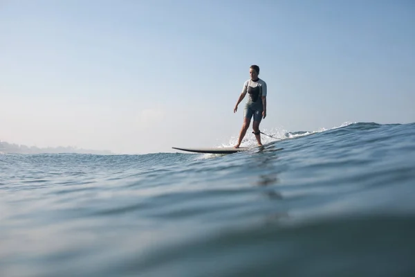 海でサーフボードの上に立ってスポーツウーマン  — 無料ストックフォト