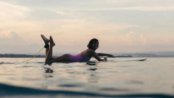 日落时分 在海洋中的水冲浪板上躺着的女人剪影 — 图库照片