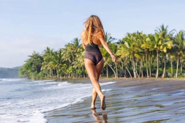 arkadan görünüşü tropikal plaj deniz kenarında koşan genç kız