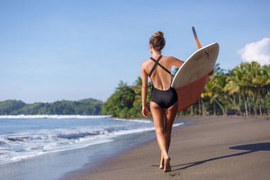 arkadan görünüşü genç sörfçü surfboard ile Sahilde yürüyüş