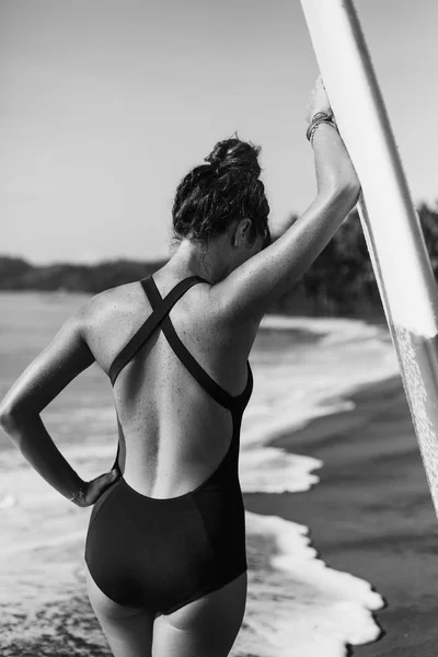 Fiatal Lány Pózol Szörf Közel Óceán Fekete Fehér Fürdőruha Hátulnézete — Stock Fotó
