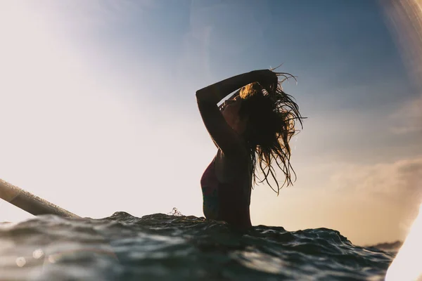 Silhueta Mulher Reajustar Cabelo Enquanto Sentado Prancha Surf Oceano — Fotografia de Stock