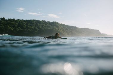genç adam sörf tahtası üzerinde güneşli günde Yüzme