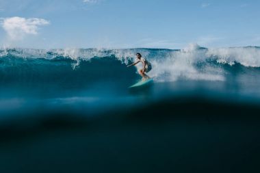 ıslak tişört güneşli günde sörf tahtası üzerinde büyük okyanus dalgaları sürme erkekte