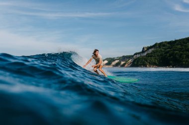 ıslak tişört sörf tahtası üzerinde mavi okyanus dalgaları sürme erkekte yan görünüm