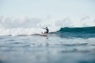 Dalgalar sörf tahtası üzerinde güneşli günde sürme wetsuit genç sporcu