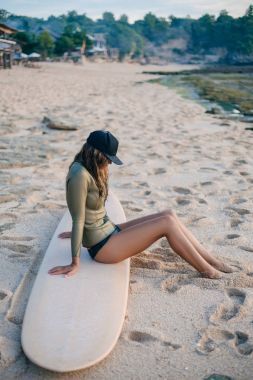 wetsuit rahatlatıcı sahil üzerinde sörf tahtası üzerinde genç kadın