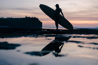Sahil akşam üzerinde surfboard ile genç kadın silüeti