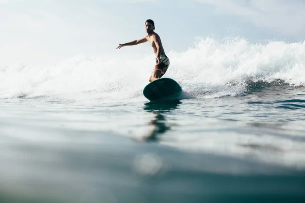 ハンサムな男性が休暇をしながらサーフボードで波に乗って — ストック写真