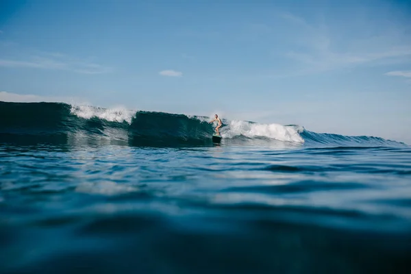 サーフボードで波に乗って若いスポーツマン  — 無料ストックフォト