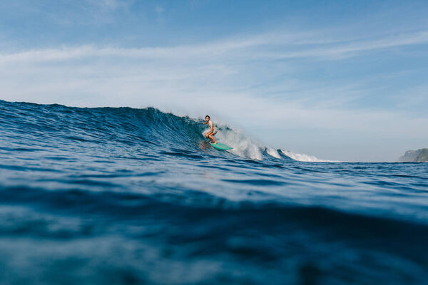 handsome man riding waves on surfboard on sunny day