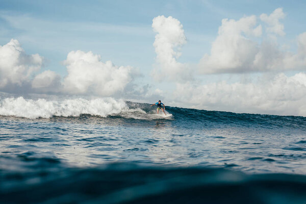 young sportsman in wetsuit having fun on surfboard on sunny day