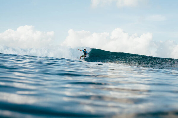 young athletic sportsman in wetsuit surfing on sunny day