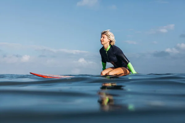 Sportswoman sitting on surf board in water — Stock Photo