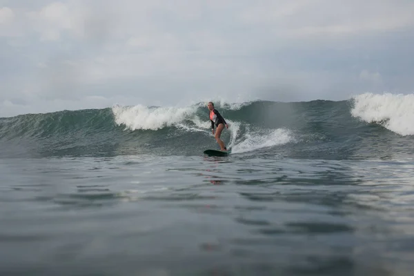 Girl riding wave on surf board in ocean — Stock Photo