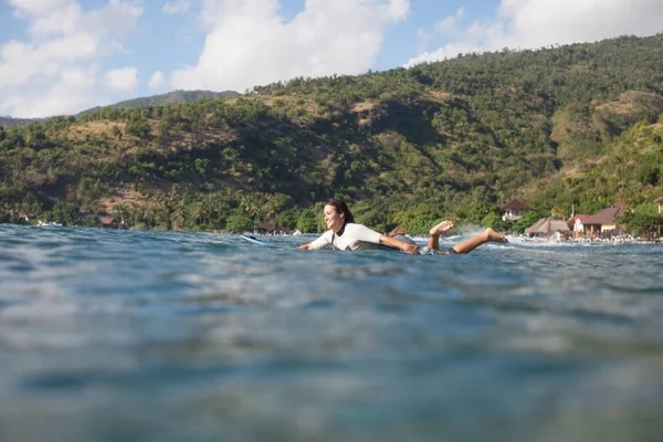 Femme nageant en planche de surf dans l'océan, littoral en arrière-plan — Photo de stock