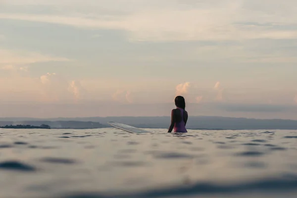 Silhouette of surfer sitting on surfboard in sea at sunset — Stock Photo