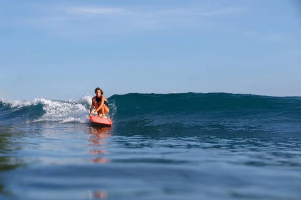 Joven surfista hembra cabalgando ola en tabla de surf - foto de stock