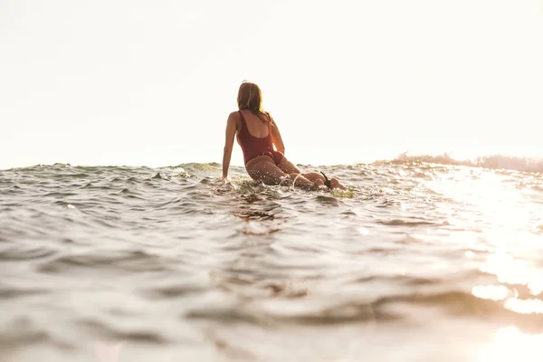 Visão traseira da mulher em roupa de banho surfando no oceano — Fotografia de Stock