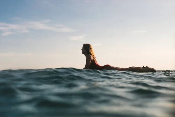 Side view of woman in swimming suit surfing alone in ocean — Stock Photo