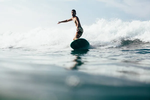 Schöner Mann, der im Urlaub Wellen auf dem Surfbrett reitet — Stockfoto