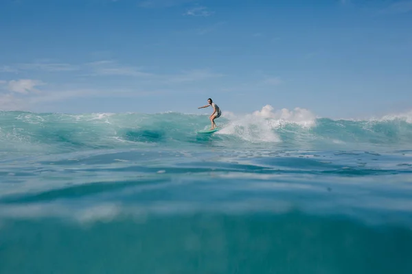 Giovane uomo cavalcando onde blu oceano su tavola da surf — Foto stock