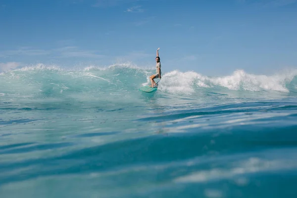 Молодий чоловік їде блакитними океанськими хвилями на дошці для серфінгу в сонячний день — стокове фото