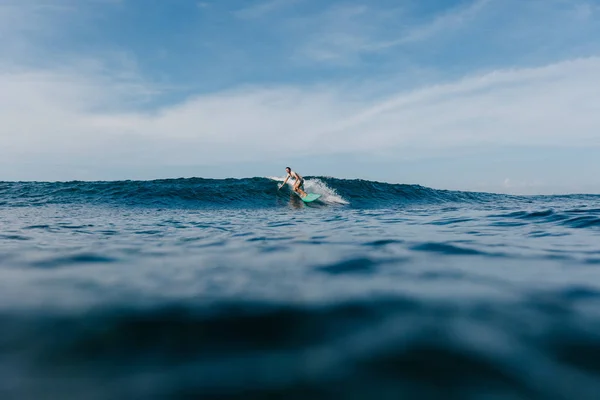 Bell'uomo cavalcando onde blu oceano su tavola da surf — Foto stock