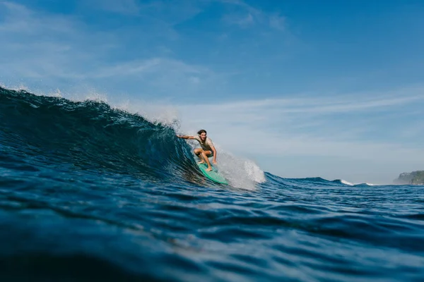 Surfeur professionnel en t-shirt mouillé équitation vagues sur planche de surf le jour ensoleillé — Photo de stock