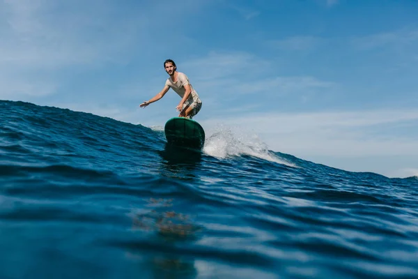 Junger Mann reitet an sonnigem Tag auf Wellen auf Surfbrett — Stockfoto