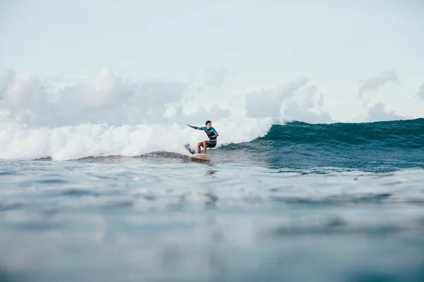 Young sportsman in wetsuit riding waves on surfboard on sunny day — Stock Photo