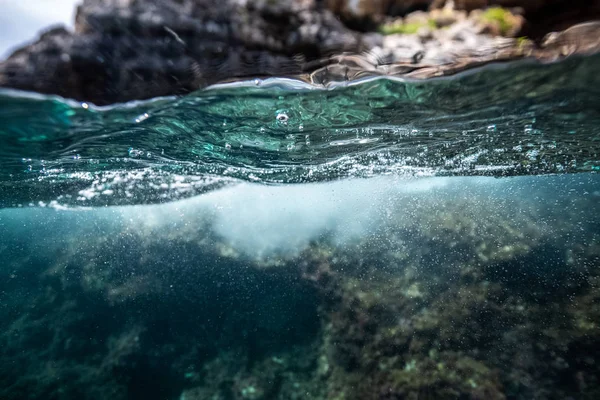 Half onder water geschoten op een prachtige baai in Palma de Mallorca, kustlijn waterlijn macro shot, onderwater fotografie met een koepelpoort — Stockfoto