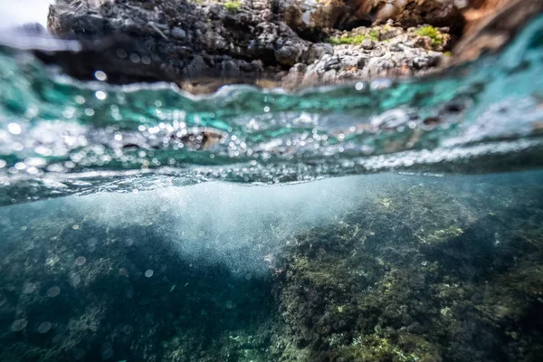 Half onder water geschoten op een prachtige baai in Palma de Mallorca, kustlijn waterlijn macro shot, onderwater fotografie met een koepelpoort — Stockfoto