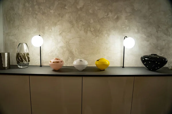 Bureau avec une grande lumière et un vase dessus, vase sur un bureau, grande texture sur un mur avec un bureau au premier plan — Photo