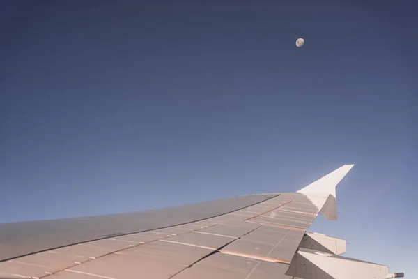 Φτερό αεροπλάνου μέσα από το παράθυρο του αεροπλάνου με το φεγγάρι στο παρασκήνιο — Φωτογραφία Αρχείου